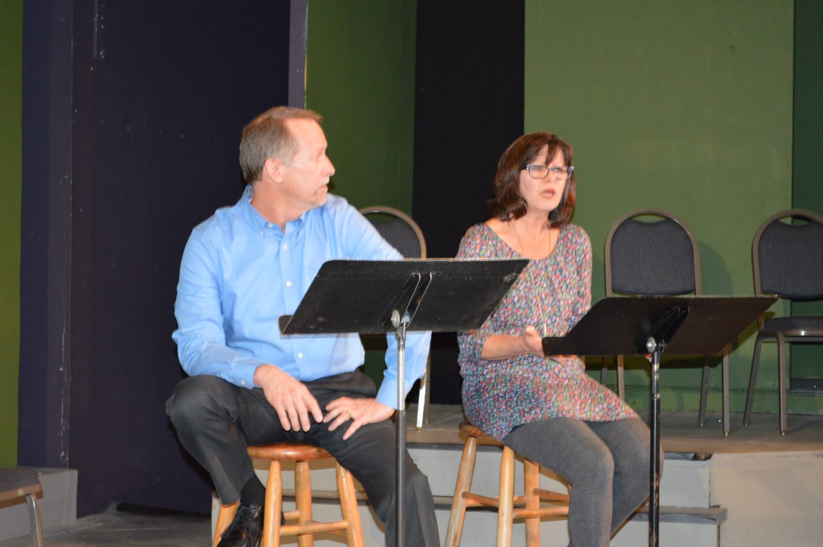 Two readers share a passage from a stool
