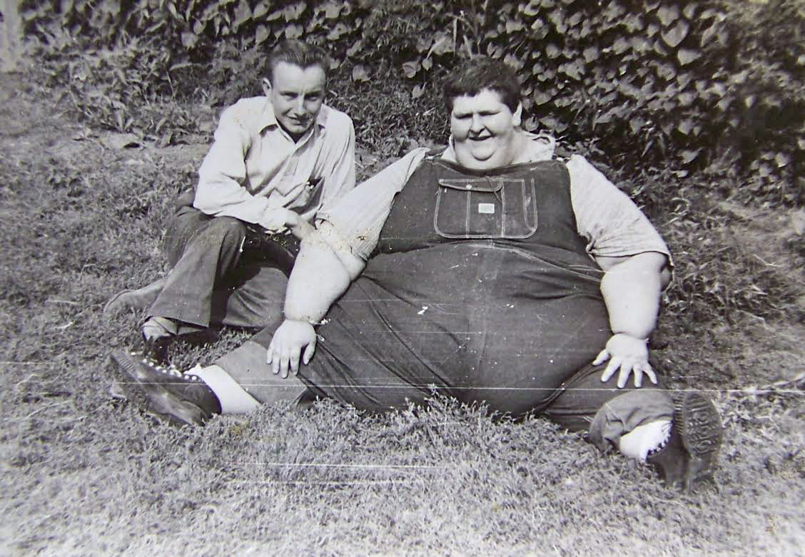 Robert Earl Hughes seated on the grass with a companion