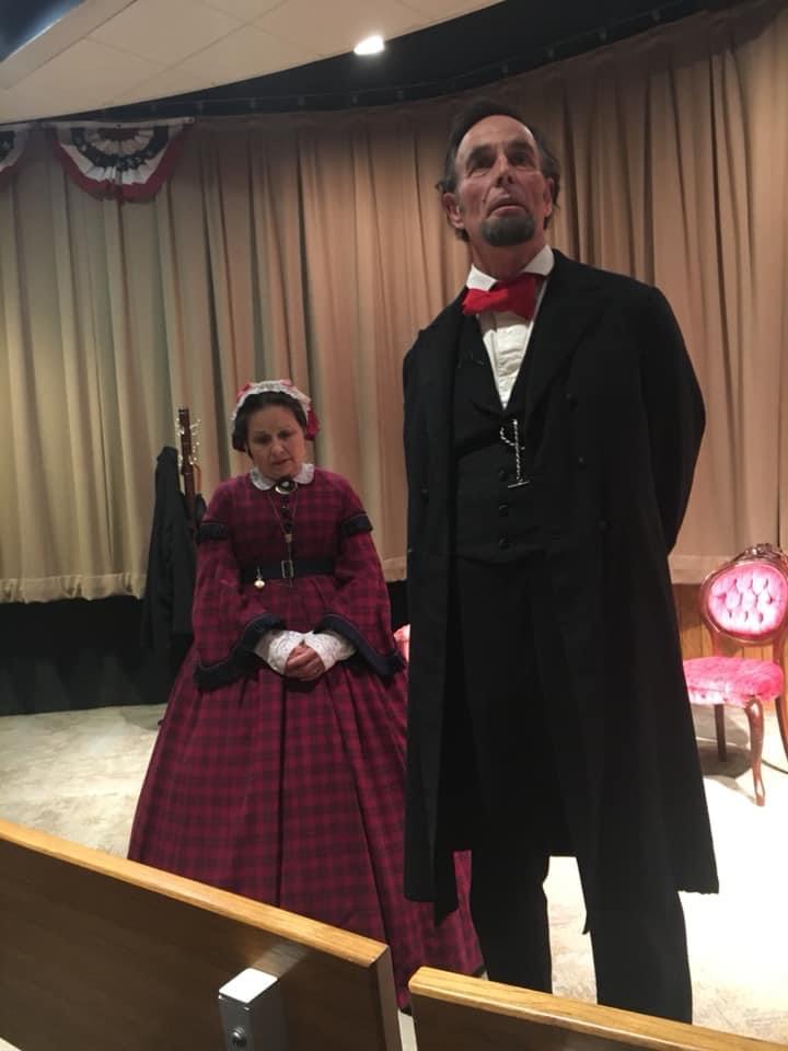 Mary Todd Lincoln seated beside Lincoln, both standing, in the Visitor Center set